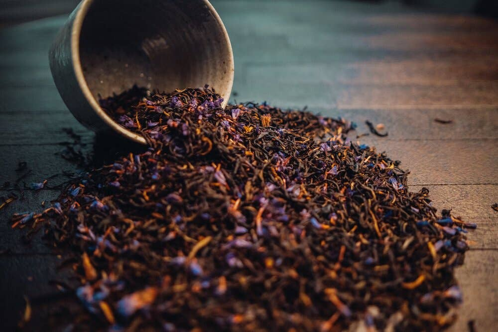 Earl Grey tea leaves pouring from a bowl onto a table