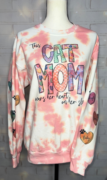 Pink tie-dye sweatshirt with 'CAT MOM' text and paw print hearts on sleeves