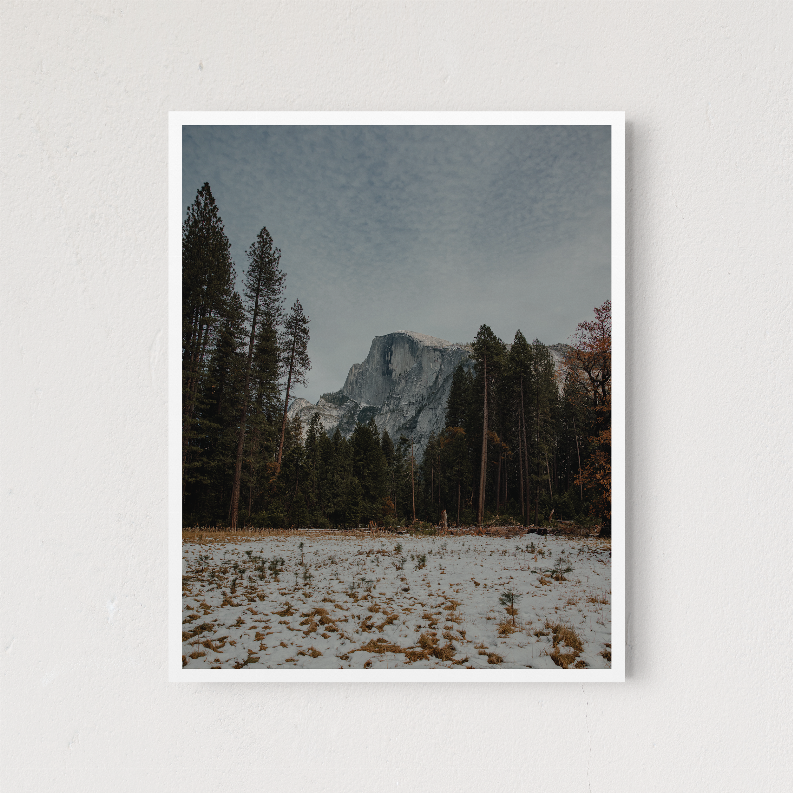 Framed landscape print showing snowy pines and granite peak, white frame