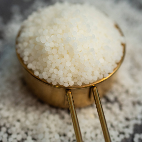 White beeswax pellets in a metal scoop, 100% pure wax beads