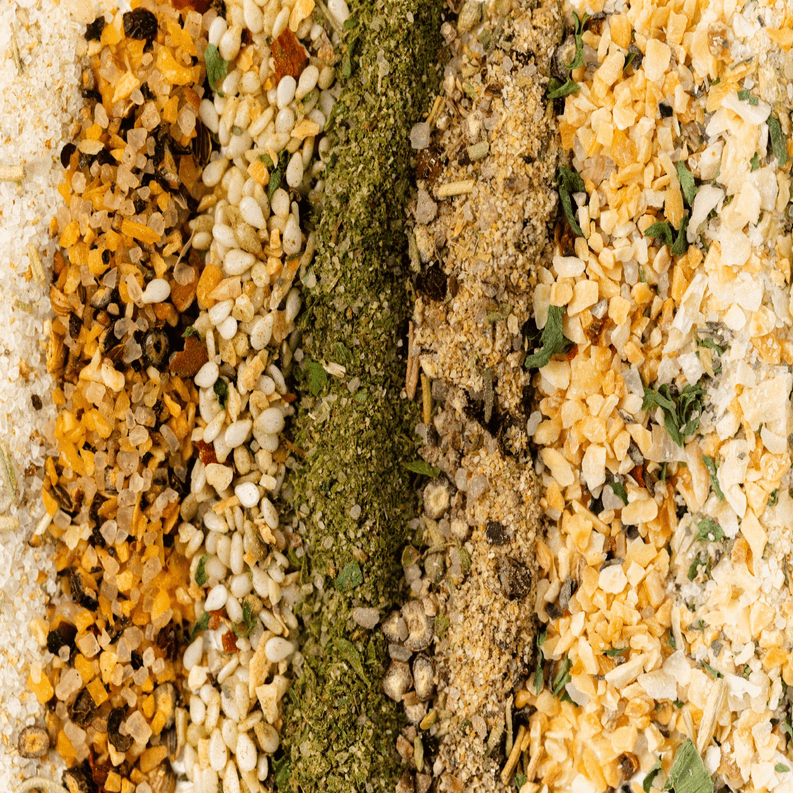 Mixed gourmet seasoning blend close-up with green, brown, and orange speckled grains