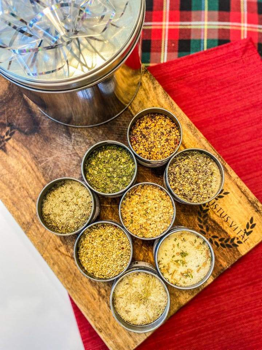 Gourmet seasoning tins set in small round jars on a wooden tray, eight varieties