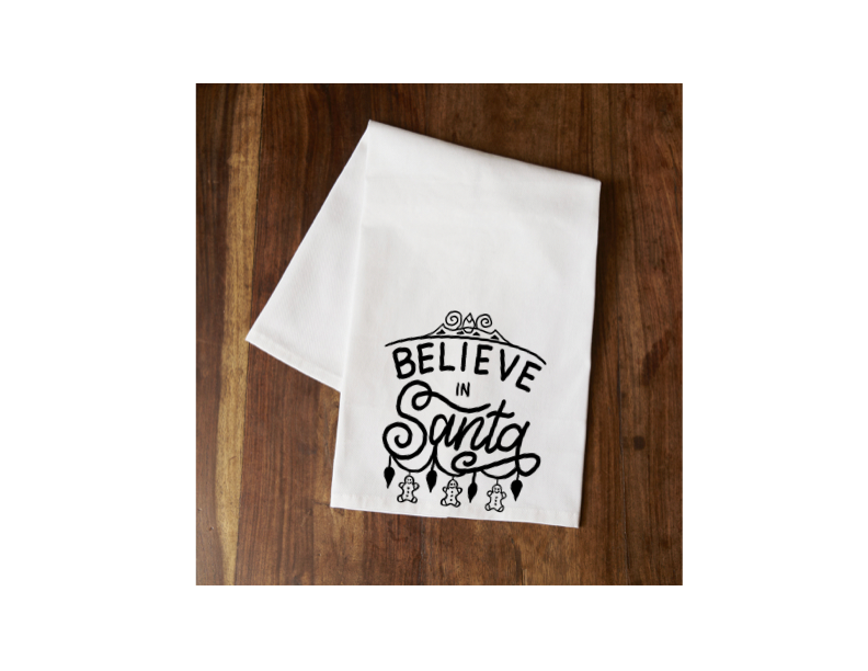White tea towel with “Believe in Santa” lettered graphic