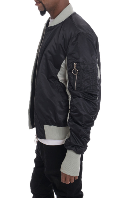 Two-tone bomber jacket, side view, black shell with light gray contrast panels and zip pocket