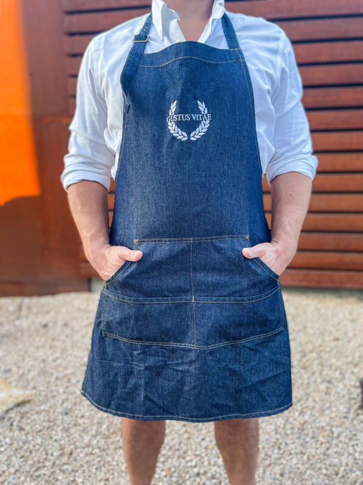 Blue denim apron with embroidered wreath logo, adjustable neck strap and chest pocket