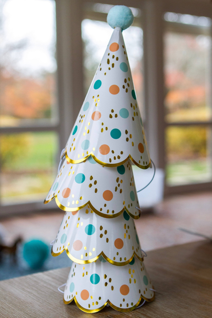 Stacked white cone party hats with light blue pom-poms and colorful polka dots