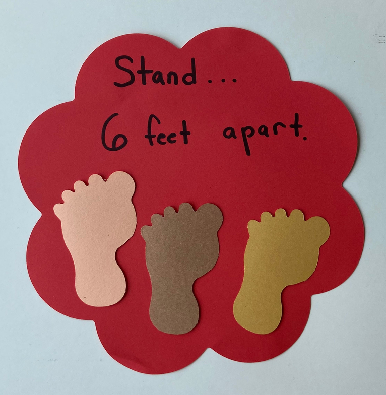 Red flower cut-out with footprints and handwritten “6 feet apart” message