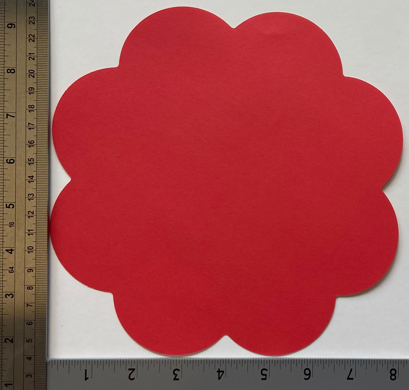 Red flower cut-out with scalloped edges beside a measuring ruler