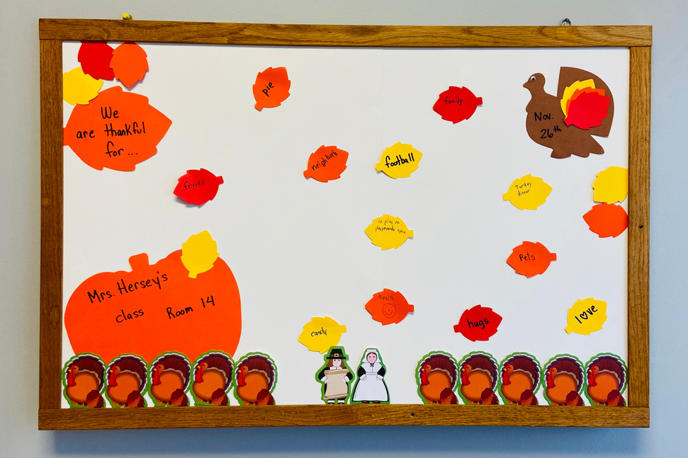 Orange pumpkin-shaped cut-out designs on a display board with multiple faces and text
