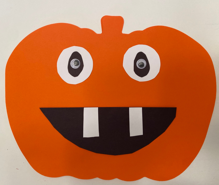 Orange pumpkin cut-out with black mouth, striped teeth, and two large white eyes