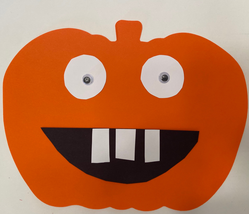 Orange pumpkin cut-out with black mouth, striped teeth, and white eyes with dark pupils