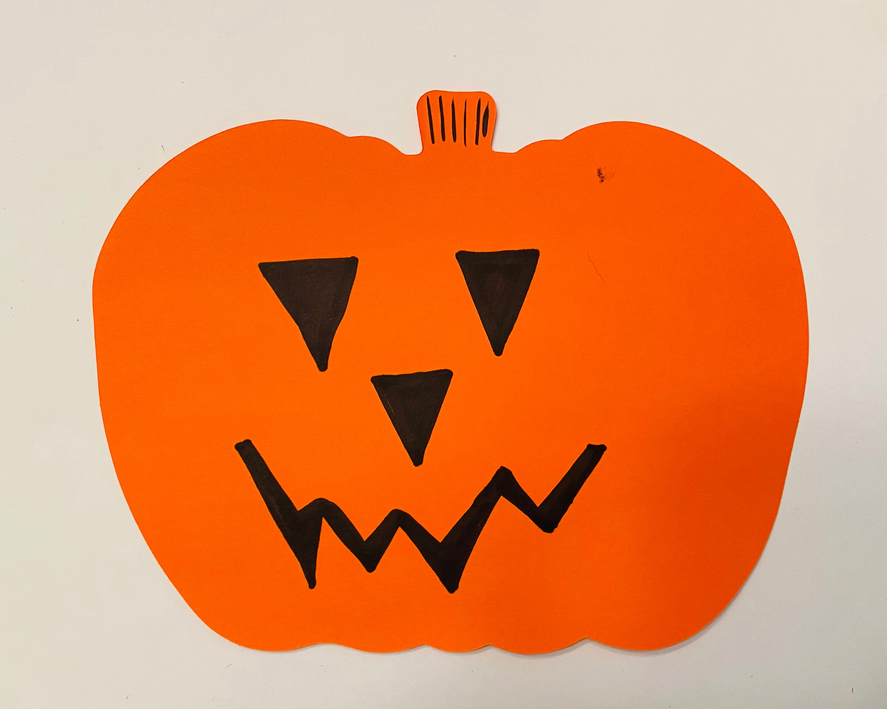 Orange pumpkin cut-out with black jack-o'-lantern grin and jagged tooth shapes