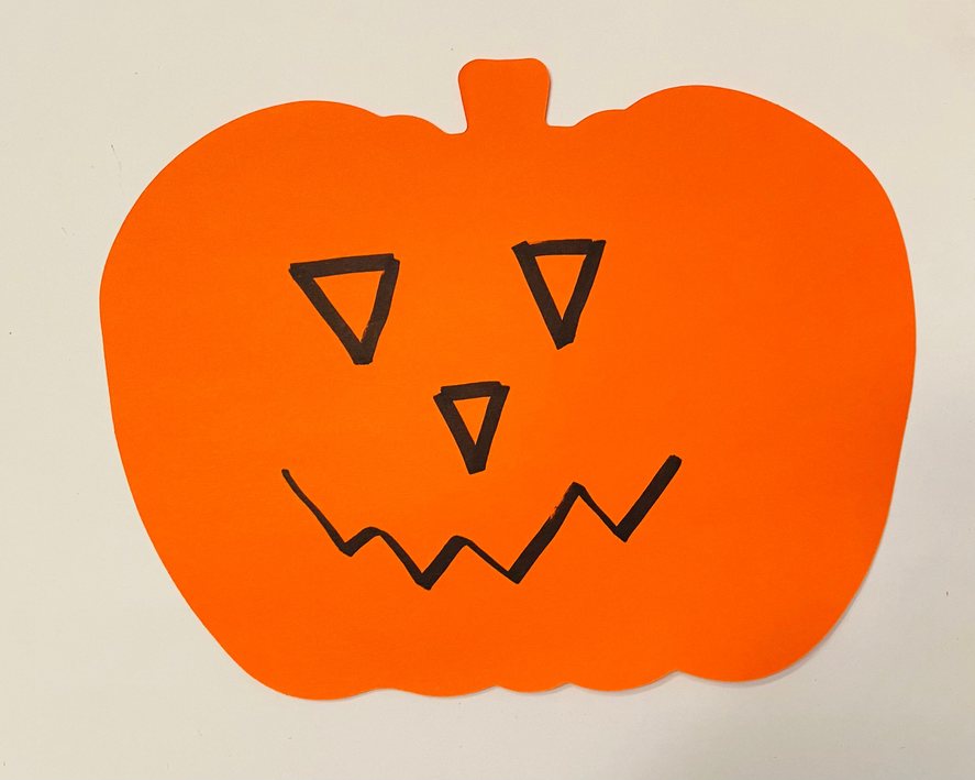 Orange pumpkin cut-out with black triangular eyes and jagged jack-o'-lantern smile