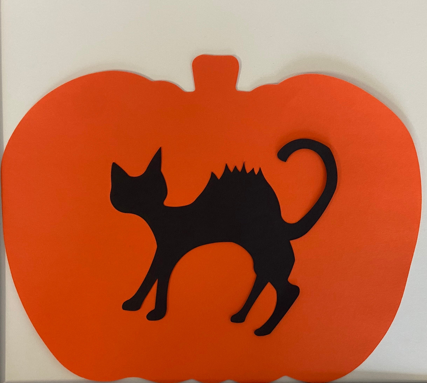 Orange pumpkin cut-out with black cat silhouette and swirled tail shape
