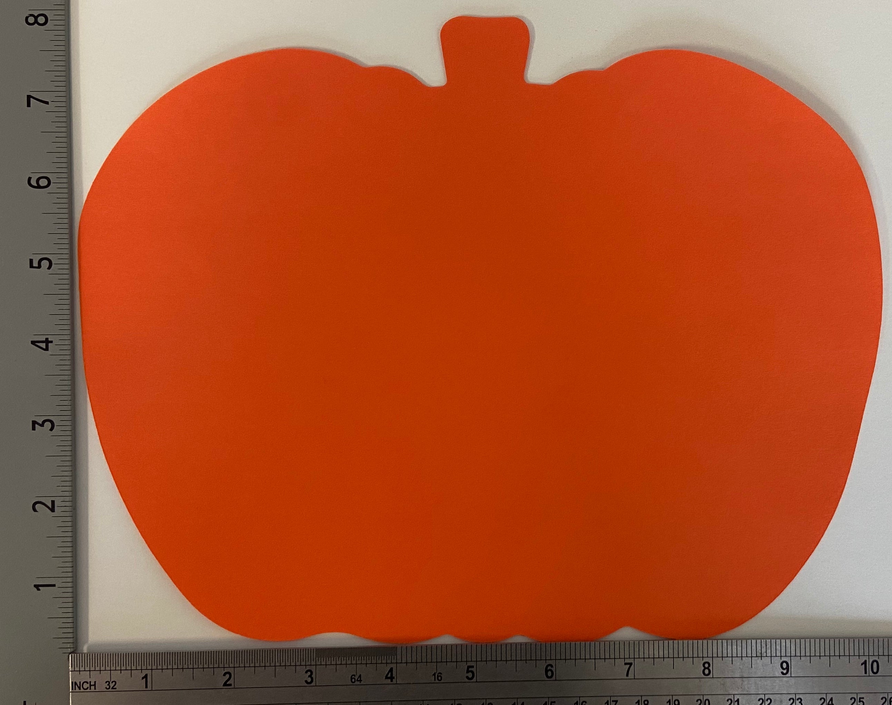 Orange pumpkin cut-out blank shape on a white background with measuring ruler edge