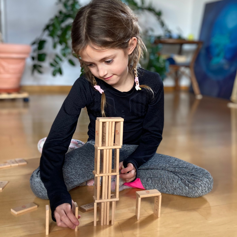 Wooden math domino set with number tiles and small rack pieces, played on floor
