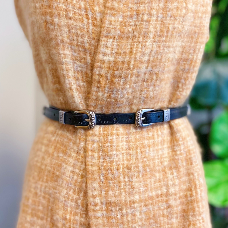 Double buckle leather belt at waist, dark blue strap with silver buckle hardware.