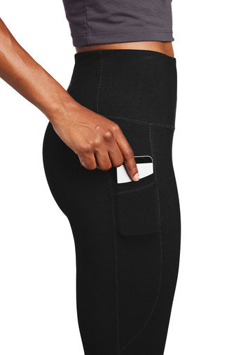 Women's black leggings with thigh pocket holding a phone