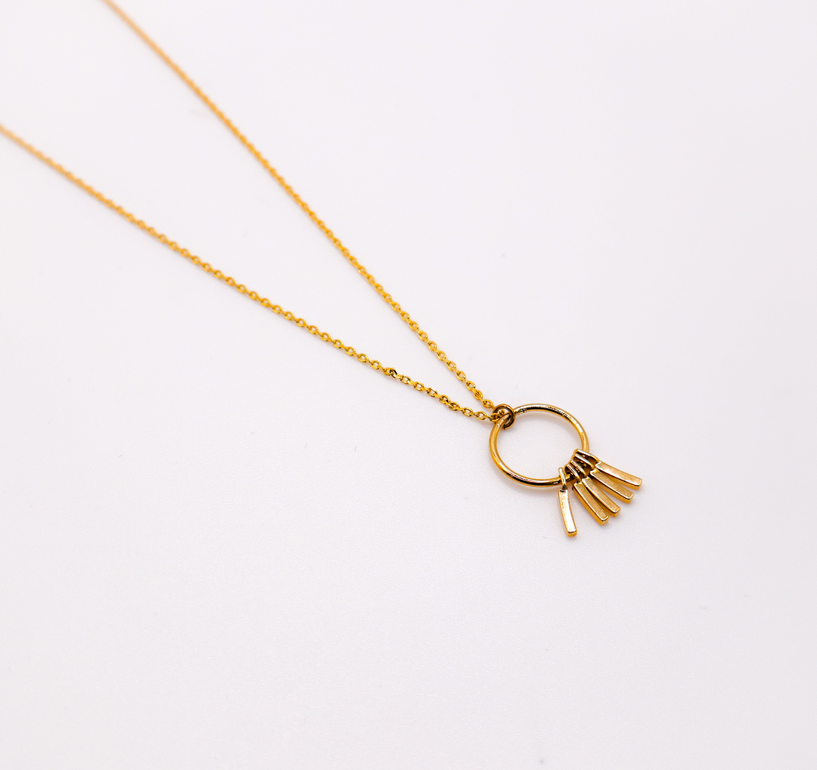 Gold chain necklace with circular hoop pendant and tassel charm detail