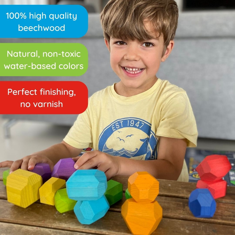 Young child smiling beside multicolor wooden balancing stones on a tabletop