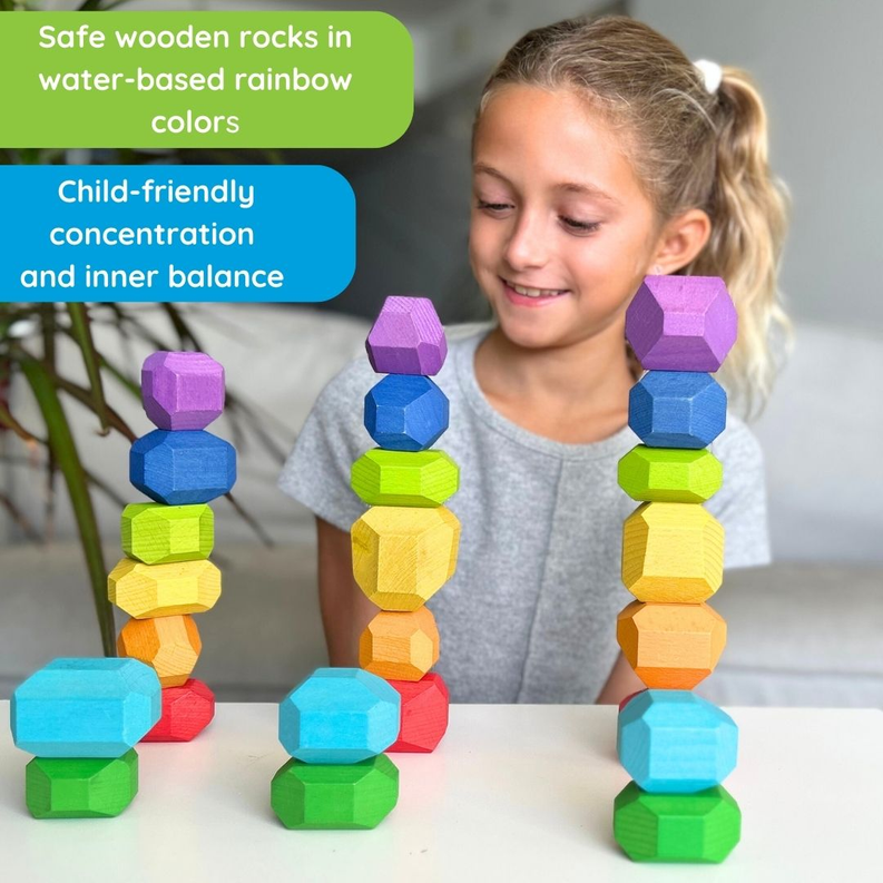 Child playing with multicolor wooden balancing stone towers on a table