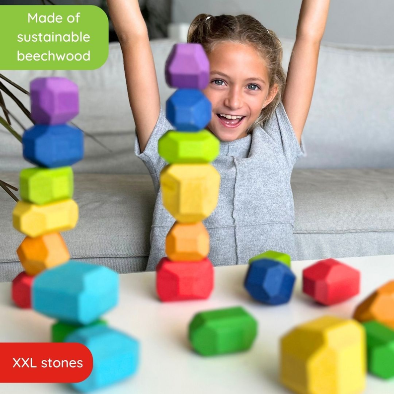 Child cheering with multicolor wooden balancing stones scattered around the floor