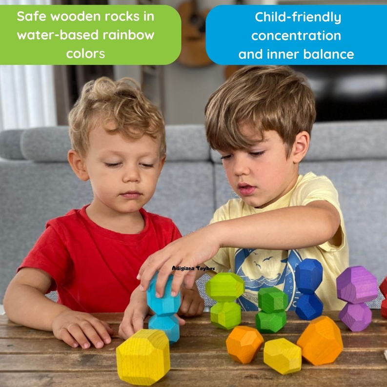 Two children playing with multicolor wooden balancing stones on a wooden table