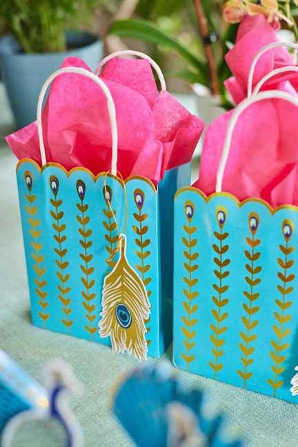 Teal tropical gift bag with feather print and white rope handles, pink tissue inside