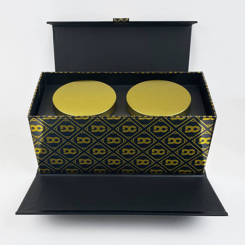 Open candle gift box with two gold-top wax pieces in patterned insert