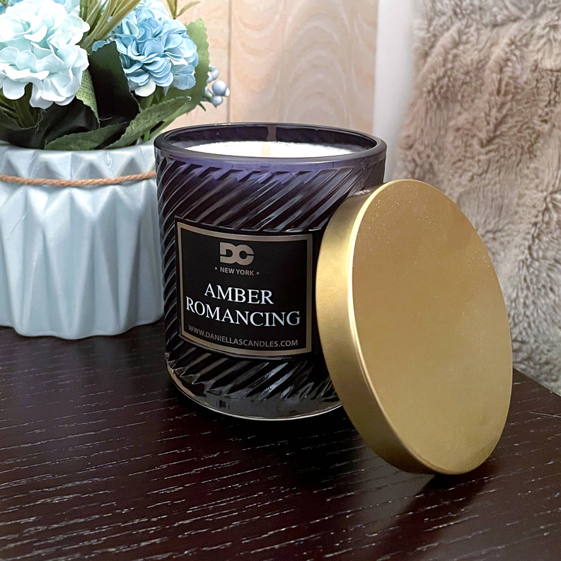 Amber romancing scented candle in dark purple glass jar with gold lid