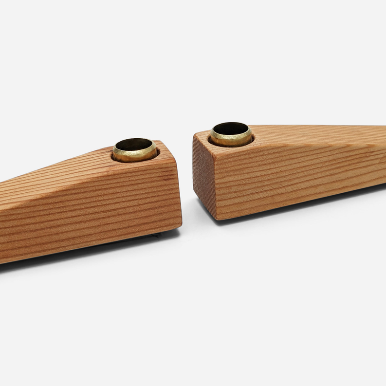 Wooden candle holder with two black metal cups, angled close-up view