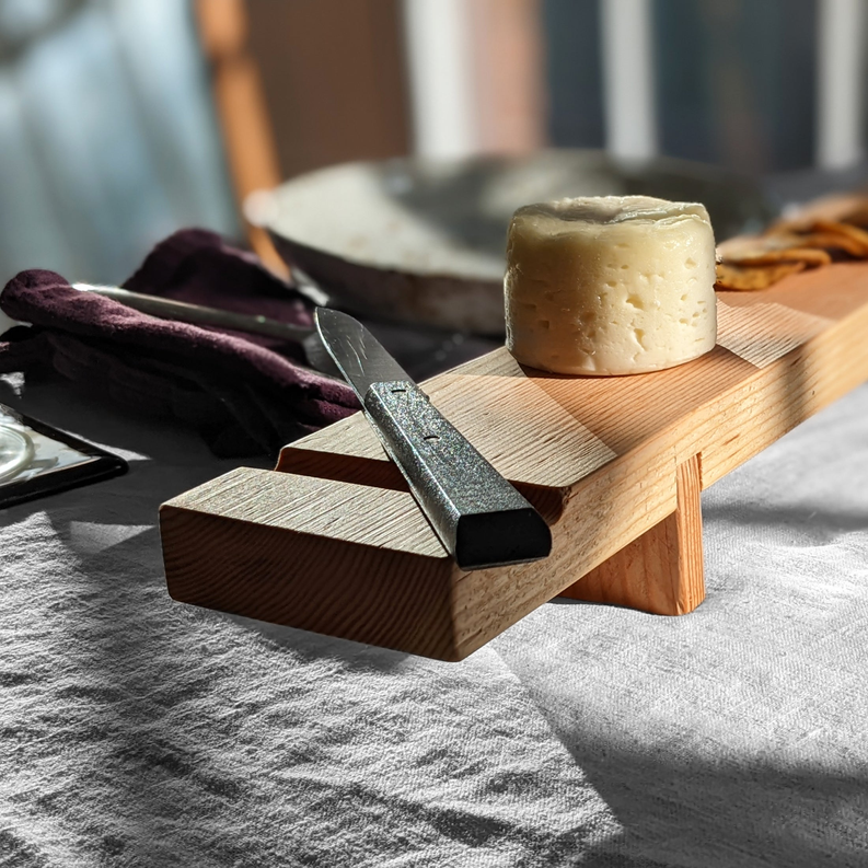 Wood charcuterie board with raised center channel, holding a cheese block.