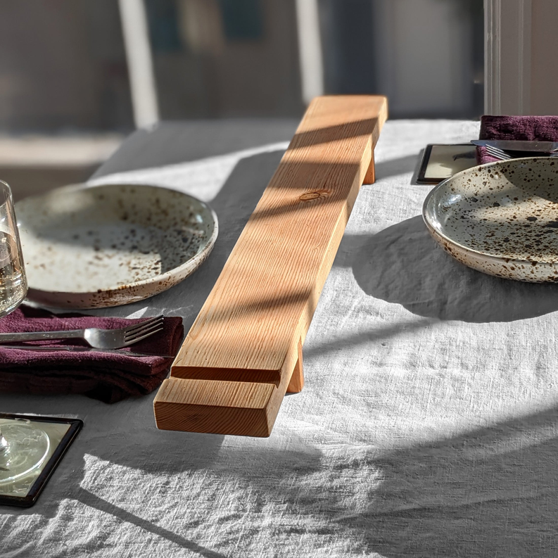 Wood charcuterie board with end handles, set on a serving table.