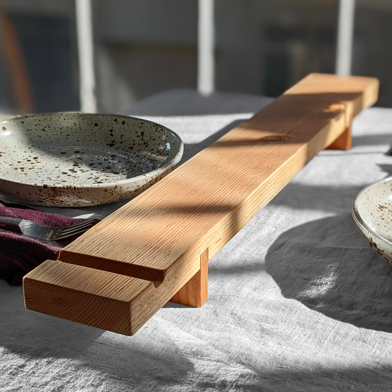 Wood charcuterie board with smooth center groove, shown with bowls and napkin.