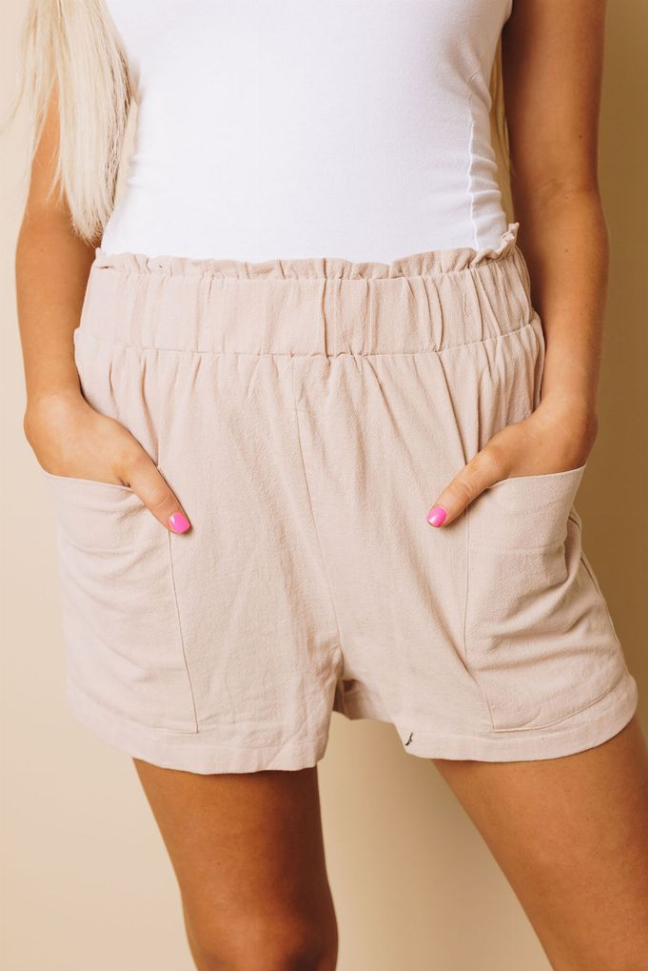 Light beige shorts with elastic waistband and side pockets, back view