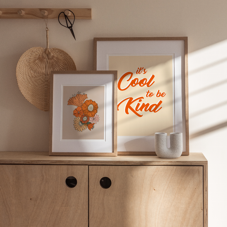 Wood framed wall art with orange "Cool to be Kind" text and small floral print