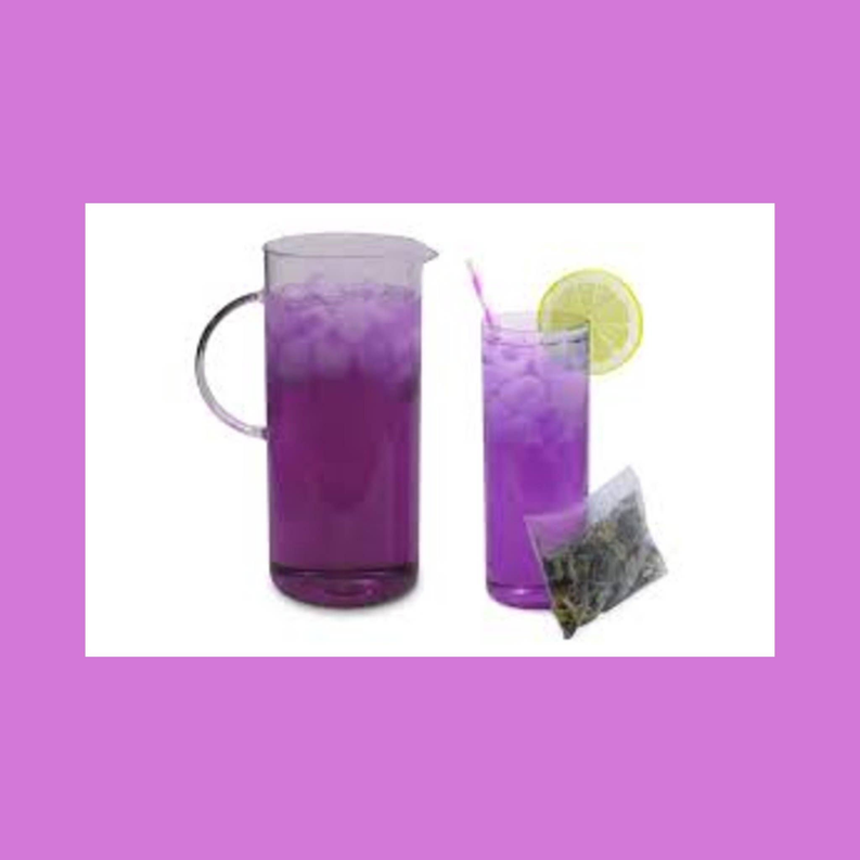 Violet berry iced tea in purple glass with tea bag and lime slice