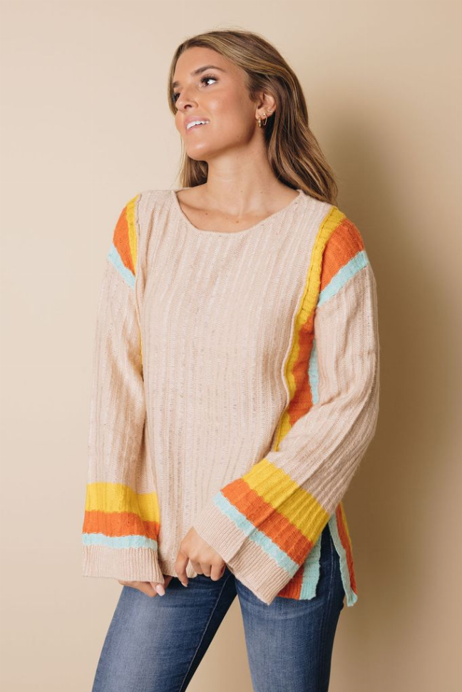 Cream knit sweater with rainbow stripe cuffs and wide neckline, side view