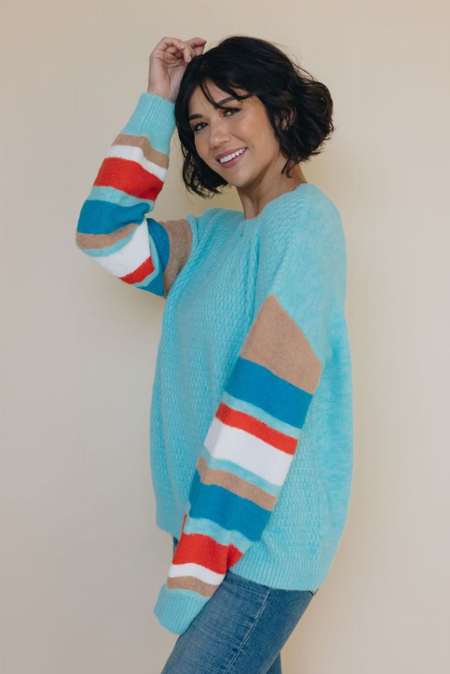 Light blue striped sweater with bold multicolor sleeve stripes, crew neck, side view