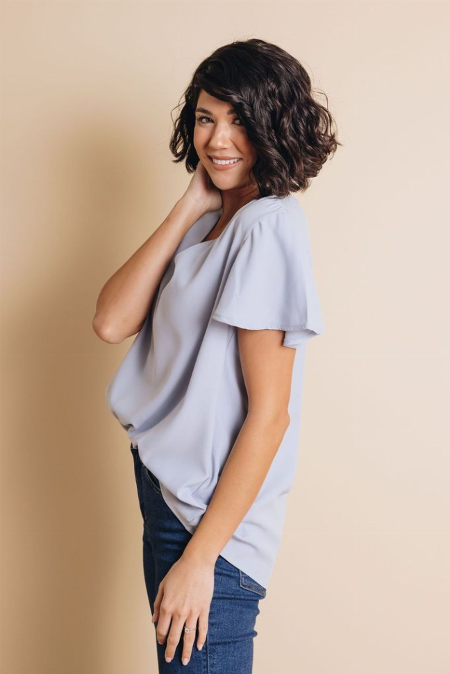 Light blue V-neck short-sleeve top with draped front and softly flared sleeves