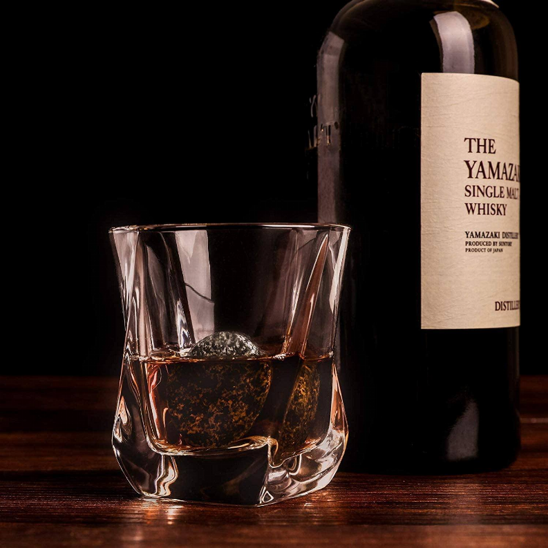 Clear whiskey tumbler with a round chilling stone inside on a wooden surface
