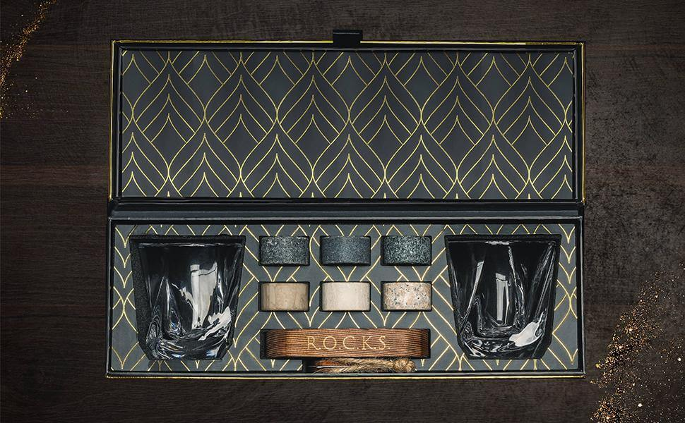 Open black gift box with patterned lining and whiskey chilling stones on a wooden base