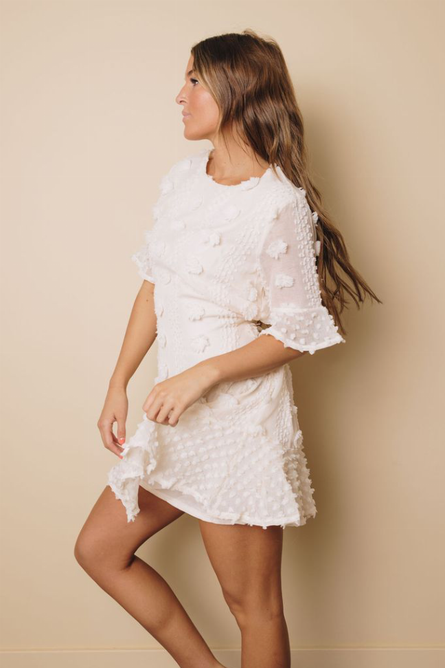 White swiss dot mini dress with ruffled sleeves and layered hem, side view