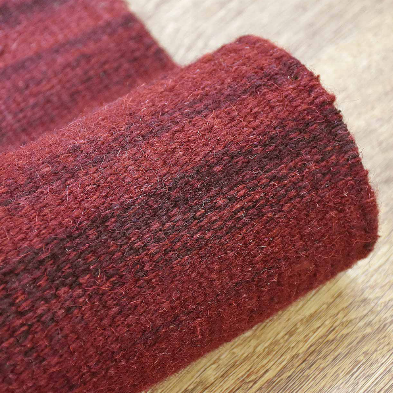 Burgundy wool flat-weave kilim rug corner with visible woven pattern