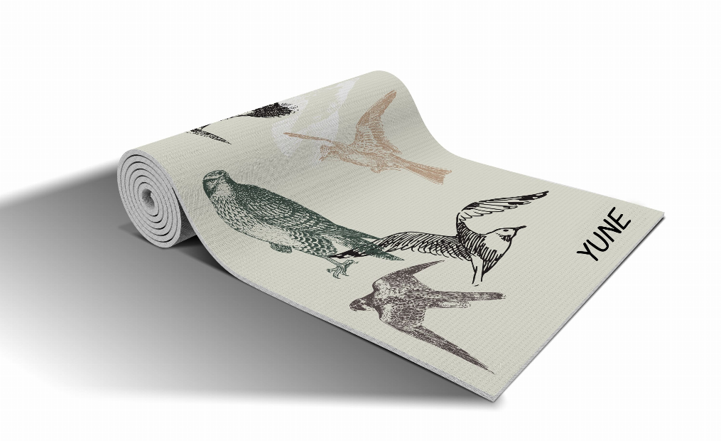 Light beige yoga mat with bird pattern, rolled and ready for yoga