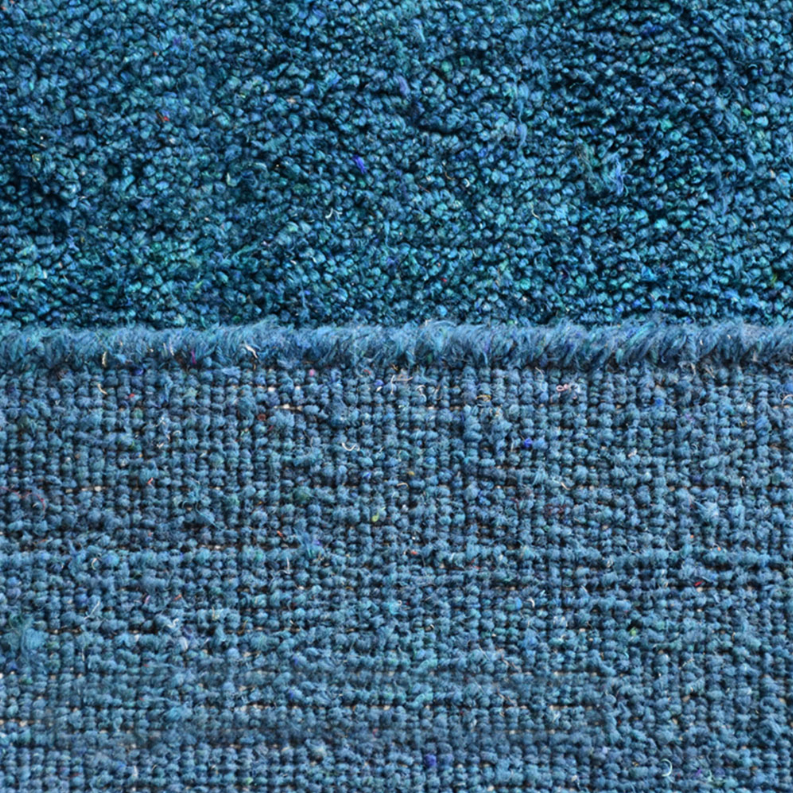 Blue area rug border close-up, dense pile with visible edge stitching
