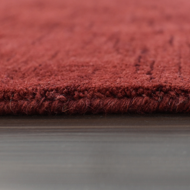 Red wool rug close-up, thick pile along the edge