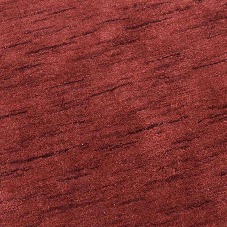 Red wool rug surface close-up with short pile and subtle streak texture
