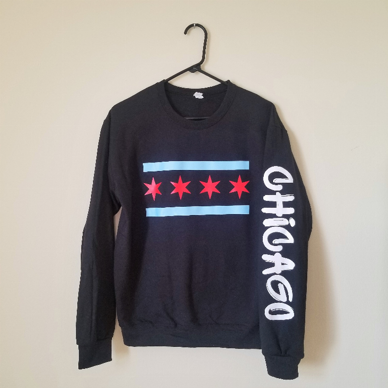 Navy crewneck sweatshirt on hanger with blue stripe, red stars, and white side text