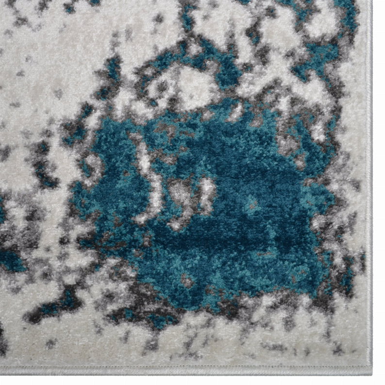 Abstract area rug with plush gray, white, and teal-blue distressed pattern